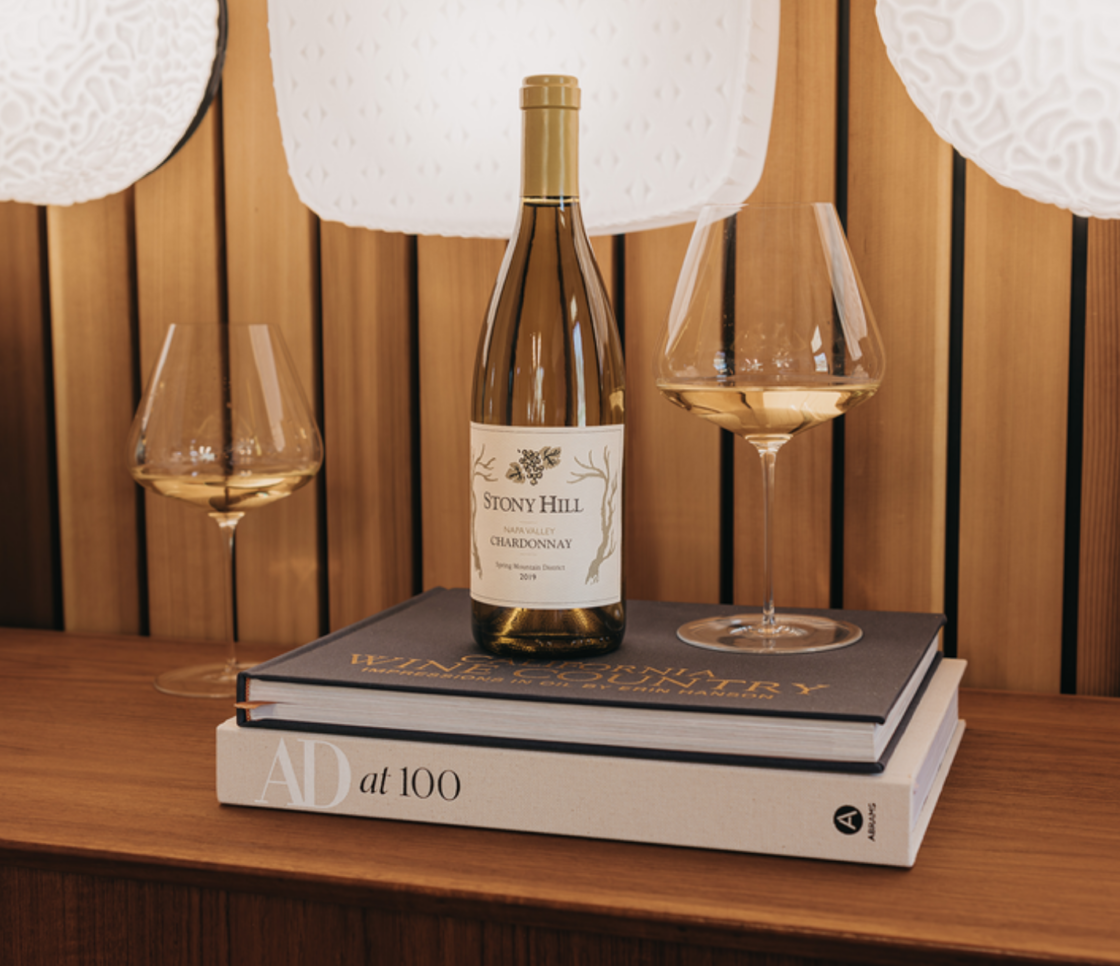 Image of a bottle of organic Chardonnay wine on a book with two wine glasses